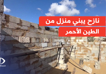 فلسطيني يبني بمنزلا من الطين الأحمر وحجارة الركام في قلب خانيونس